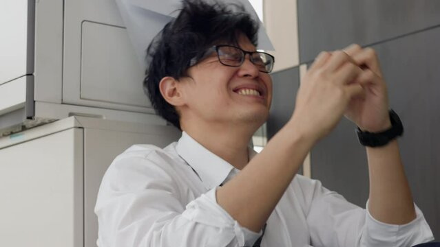 Overload office worker. Alone stressed and sad  asian office worker is sitting beside error copy machine at the office.