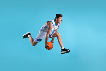 Obraz premium Professional sportsman playing basketball on light blue background
