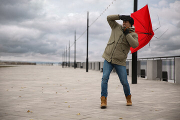 Man with red umbrella caught in gust of wind outdoors