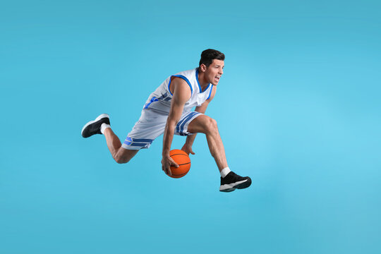 Professional sportsman playing basketball on light blue background
