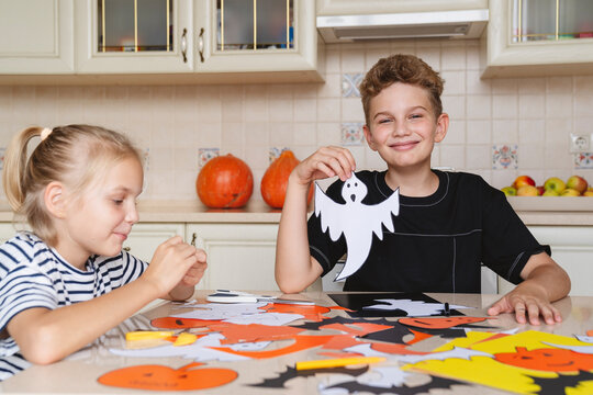 Children prepare crafts made of colored paper for the Halloween.
