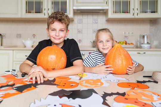 Children with pumpkins are preparing crafts for the Halloween holiday.