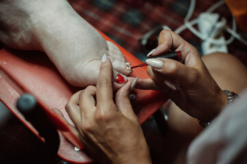 Obraz premium Pedicurist paint nails with red nail polish on client's foot