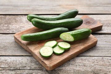 Whole and cut fresh ripe cucumbers on wooden table