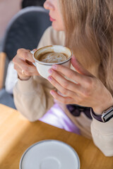 The girl is holding a cup of coffee in her hands