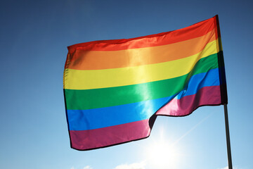 Bright LGBT flag fluttering against blue sky