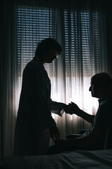 silhouette of two people inside a room. one of them shakes hands as an aid to a seated adult