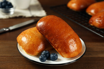 Delicious baked pirozhki with blueberries on wooden table, closeup