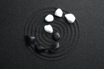 Stones on black sand with beautiful pattern, flat lay. Zen and harmony