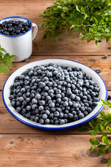 Frozen blueberries in a metal bowl on wooden table