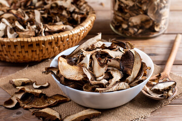 Dried mushrooms sliced, on a plate on wooden background - obrazy, fototapety, plakaty