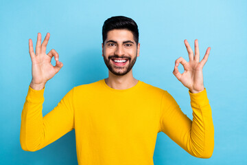 Fototapeta premium Photo of cheerful confident guy dressed yellow pullover showing two okey signs isolated blue color background