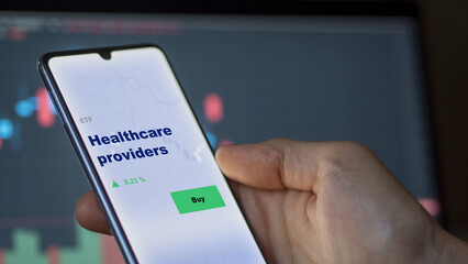 An investor's analyzing the  on screen. A phone shows the ETF's prices healthcare providers