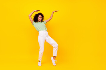 Fototapeta na wymiar Full length photo of sweet adorable girl dressed green t-shirt dancing looking empty space isolated yellow color background