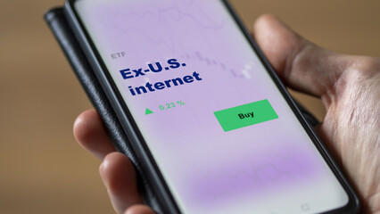 An investor's analyzing the u.s., u.s.a. etf fund on screen. A phone shows the ETF's prices ex-U.S. internet to invest