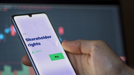 An investor's analyzing the shareholder rights etf fund on screen. A phone shows the ETF's prices stocks to invest