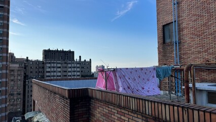 青空の下、マンションの屋上に干された布団
