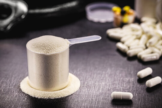 Measuring spoon with creatine or whey, and steroid pills, food supplement, casein cocktail, muscle mass vitamin, plated, bodybuilding concept