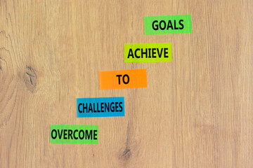 Overcome challenges to achieve goals symbol. Concept words Overcome challenges to achieve goals on color papers on a beautiful wooden background. Business goals concept. Copy space.
