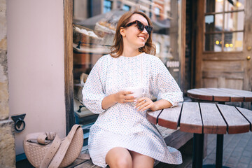 Happy woman in cafe on a city street. People, fashion, lifestyle, travel and vacations concept.