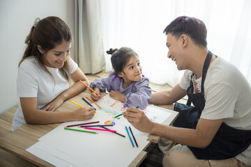 Daughter, asian child to draw picture, paint color in paper on table with parent or father, mother in room. Include blind curtain, wood floor background. Concept for family, creativity and education.