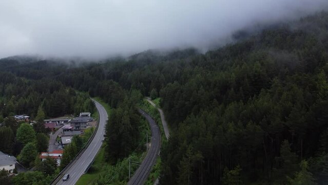 Aerial shot of the Reith bei Seefeld in Austria, with highways and green lush trees on a foggy day