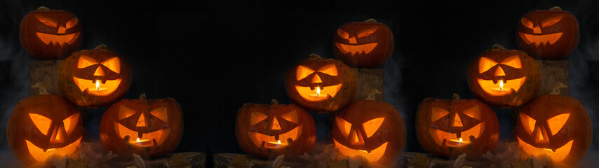 Scary Halloween celebration holiday background banner panorama - Spooky carved pumpkins and dust in the dark black night