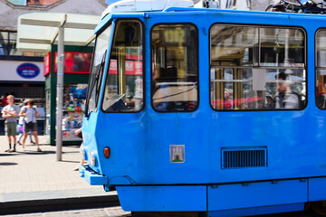 Plakat closeup of old vintage blue tram in the popular Jelacic square in downtown Zagreb. tourism and travel to croatia concept. day traffic. blurred urban background with tourists and locals. city transit 