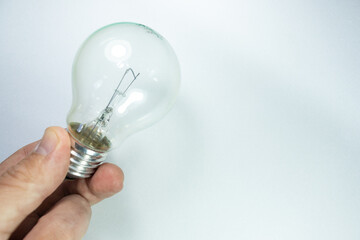 White male hand holding antique tungsten light bulb on white background, neutral