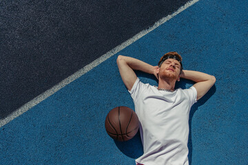 top view of young basketball player relaxing on court near ball