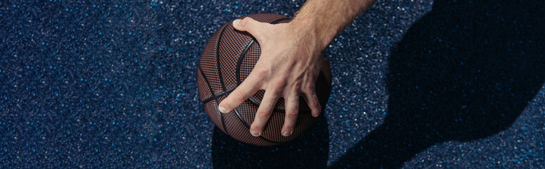 partial view of basketball player taking ball from asphalt, banner