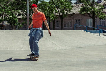 trendy man in sunglasses riding skateboard in urban park