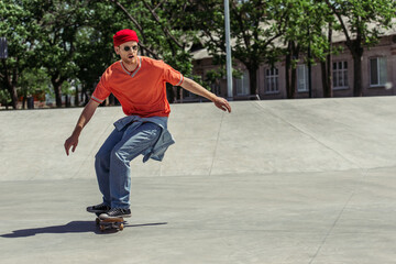 full length of man in orange t-shirt and red beanie riding in skate park © LIGHTFIELD STUDIOS
