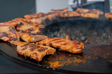 Process of cooking fresh juicy meat steaks on brazier at summer local food market - close up view. Outdoor cooking, gastronomy, cookery, street food concept