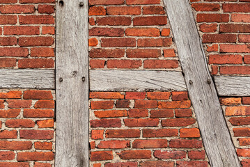 Background texture of an old timber frame wall, consisting of weathered wooden beams and red...