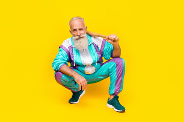 Fototapeta na wymiar Full size portrait of aged handsome person sitting arm hold baseball bat wear 90s vibe outfit isolated on yellow color background