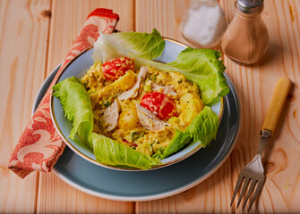 Coronation chicken with brown rice and potatoes, garnished with lettuce and tomatoes.