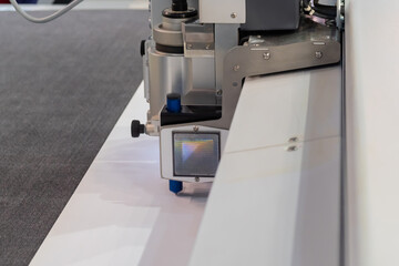 Flatbed cutter, router with drawing pen module writing text on white plastic sheet. Technology,...