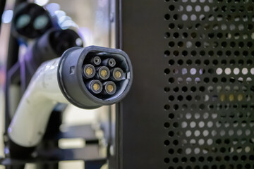 Electric charger of vehicle charging station with plug of power cable - close up view. Renewable, transport, technology, sustainable energy and futuristic concept