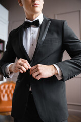 Cropped view of man buttoning jacket at home