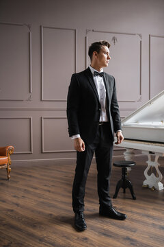 Elegant man in suit standing near piano at home