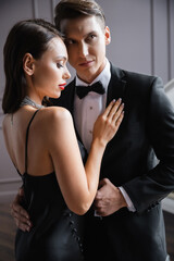 Brunette woman in dress touching boyfriend in formal wear at home