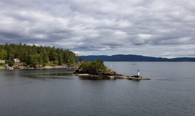 Fototapeta premium Treed Island with Homes, boats and docks, nearby smaller island with lighthouse. Summer Season. Gulf Islands near Vancouver Island, British Columbia, Canada. Canadian Landscape.