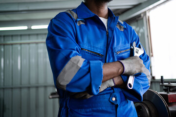 An African-American worker holds a wrench in a factory. Check the safety in the factory. Machine maintenance service concept