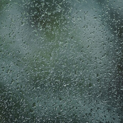 Rainy day, raindrops on wet window glass, vertical bright abstract rain water background pattern detail, macro closeup, detailed green, blue, dark vivid gray waterdrops, gentle bokeh, pluvial rainfall