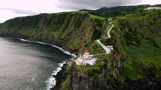 Drone flying to Lighthouse Farol Ponta do Arnel from ocean side. Aerial view of amazing landscape of green island in atlantic ocean, 4k footage. Sao Miguel, Azores, Atlantic Coastline