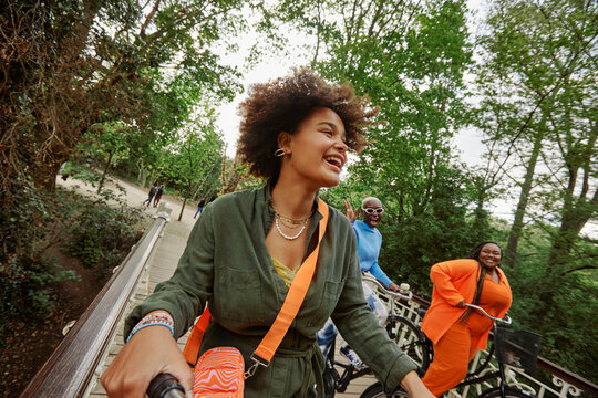 Happy female friends riding bicycles on bridge in Vondelpark