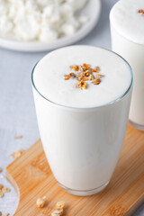 Kefir, buttermilk or yogurt, cottage cheese with granola. Yogurt in glass on light background. Probiotic cold fermented dairy drink. Gut health, fermented products, healthy gut flora concept