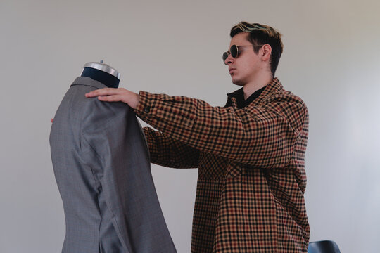 A young tailor preparing a new suit. A costume designer working on a mannequin. Tailor measuring a gray suit. High quality photo