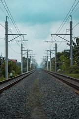 Details of the railroad track made of iron, wood and gravel in a suburban area on a cloudy day in Indonesia